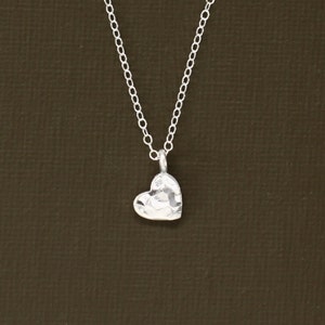 May include: A silver necklace with a hammered heart pendant.