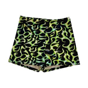 Puede incluir: Shorts estampados en negro y verde. Los shorts presentan un diseño repetitivo en forma de llama en verde brillante sobre un fondo negro. Los shorts están hechos de un material suave y elástico y tienen un ajuste cómodo.