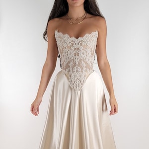 May include: A white strapless wedding dress with a lace bodice and a satin skirt.