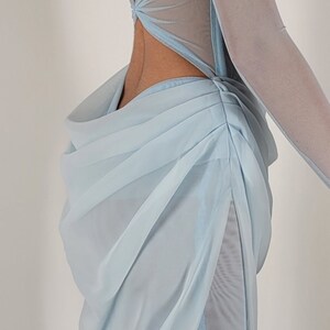 May include: A light blue, sheer, sleeveless gown with a low back and a gathered skirt. The gown has a fitted bodice with a sweetheart neckline and a beaded embellishment at the bust.
