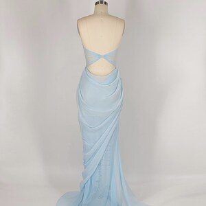 May include: A light blue, floor-length, strapless gown with a draped design and a cutout in the back.