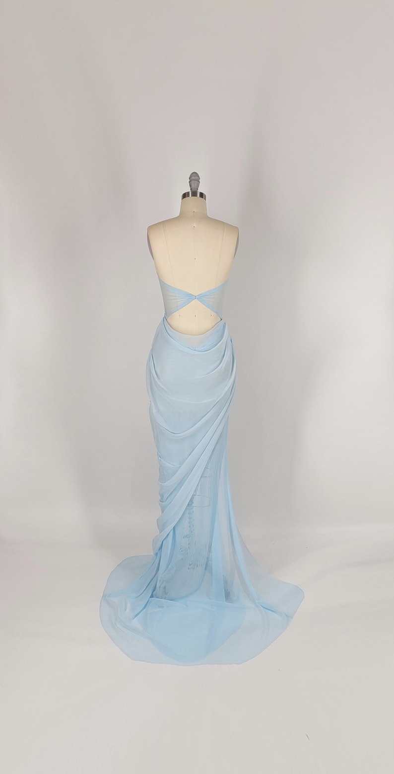 May include: A light blue, floor-length, strapless gown with a draped design and a cutout in the back.