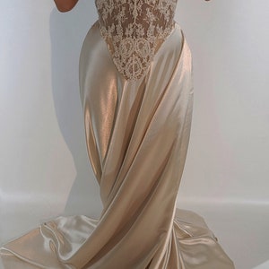 May include: A strapless, ivory lace and satin gown with a fitted bodice and a flowing skirt.