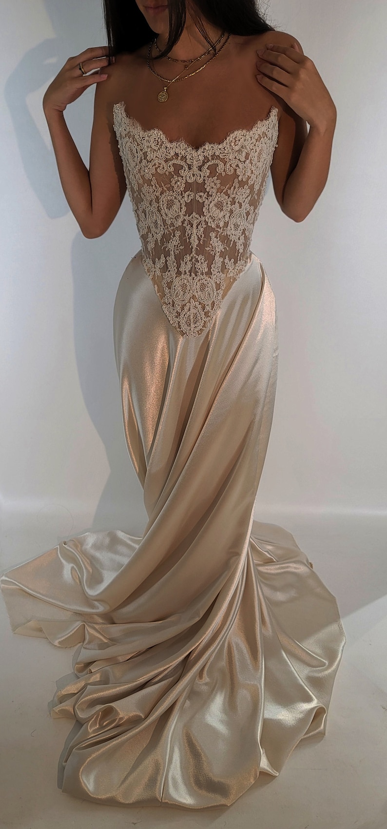 May include: A strapless, ivory lace and satin gown with a fitted bodice and a flowing skirt.