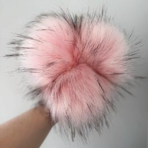 May include: A fluffy pink and black pom pom with long, soft fibers.