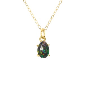 May include: A gold chain necklace with a pear-shaped black opal pendant.
