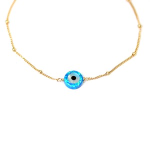 May include: A gold chain necklace with a blue and white evil eye charm. The charm is round and has a black pupil.