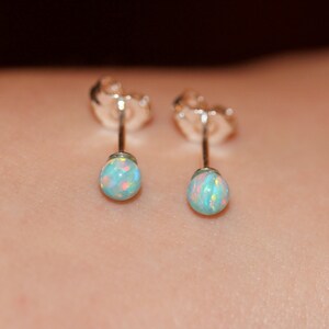 May include: A pair of silver stud earrings with small, round, iridescent opal stones.