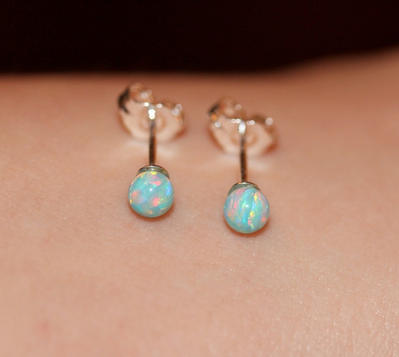 May include: A pair of silver stud earrings with small, round, iridescent opal stones.