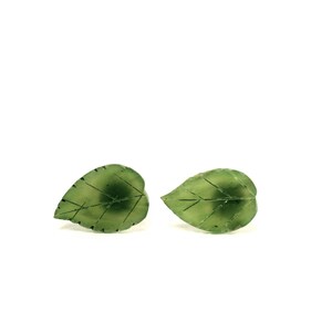 May include: A pair of green leaf-shaped earrings. The earrings are made of a translucent green material and have a delicate vein pattern.