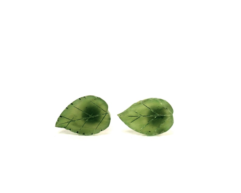 May include: A pair of green leaf-shaped earrings. The earrings are made of a translucent green material and have a delicate vein pattern.