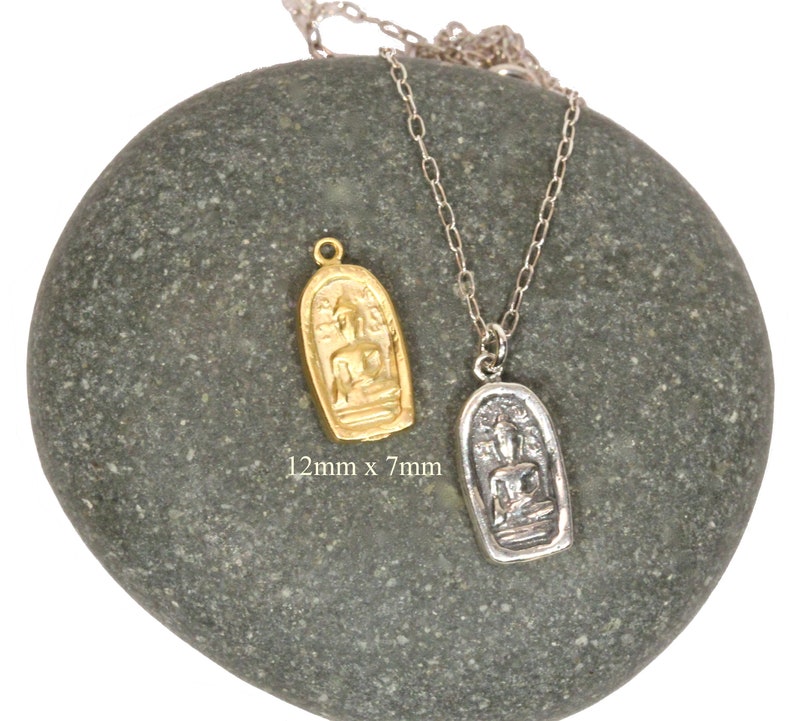 May include: Two silver necklaces with pendants featuring a seated Buddha figure. The pendant on the left is gold and the pendant on the right is silver. The pendants are 12mm x 7mm.