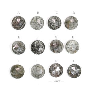 May include: Twelve round, faceted, clear quartz stones with black inclusions. Each stone is approximately 12mm in diameter. The stones are labeled A through L.