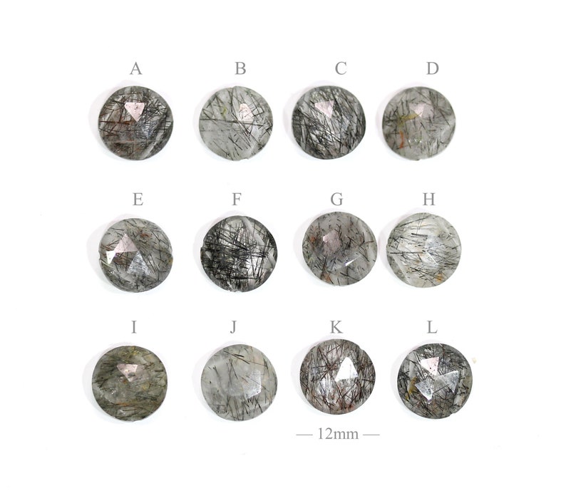 May include: Twelve round, faceted, clear quartz stones with black inclusions. Each stone is approximately 12mm in diameter. The stones are labeled A through L.