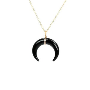 May include: A gold chain necklace with a black crescent moon pendant.