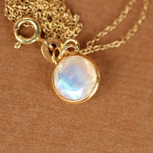 May include: A gold chain necklace with a round, iridescent moonstone pendant.
