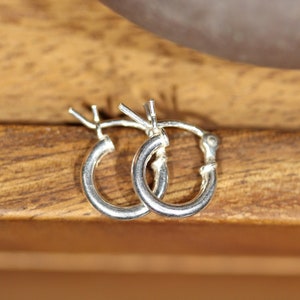 May include: A pair of silver hoop earrings. The earrings are small and delicate, and they are perfect for everyday wear.