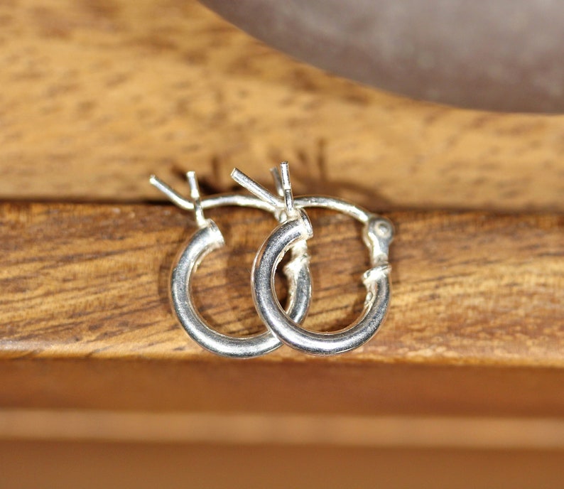 May include: A pair of silver hoop earrings. The earrings are small and delicate, and they are perfect for everyday wear.
