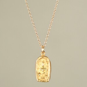 May include: A gold chain necklace with a pendant featuring a detailed image of a seated Buddha.
