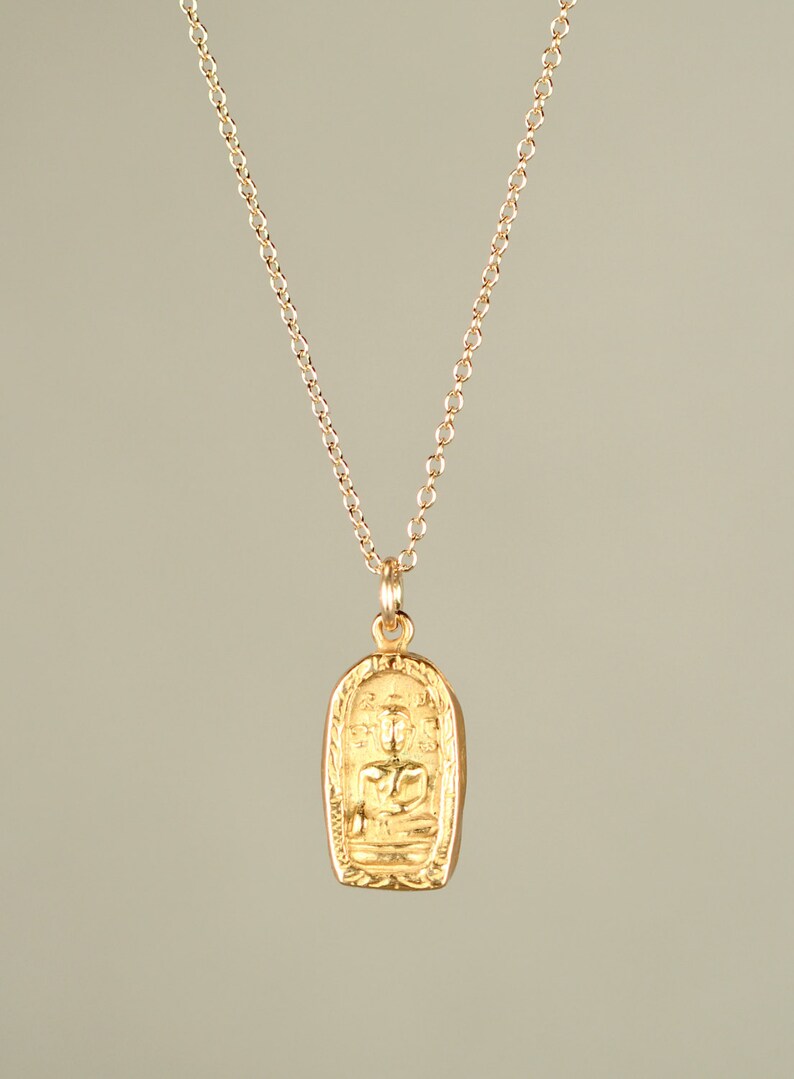 May include: A gold chain necklace with a pendant featuring a detailed image of a seated Buddha.