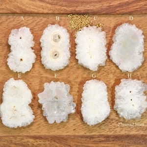 May include: Eight white quartz crystal pendants, each with a unique shape and size, arranged in two rows of four on a wooden surface. The pendants measure approximately 2.7 inches by 2.3 inches.