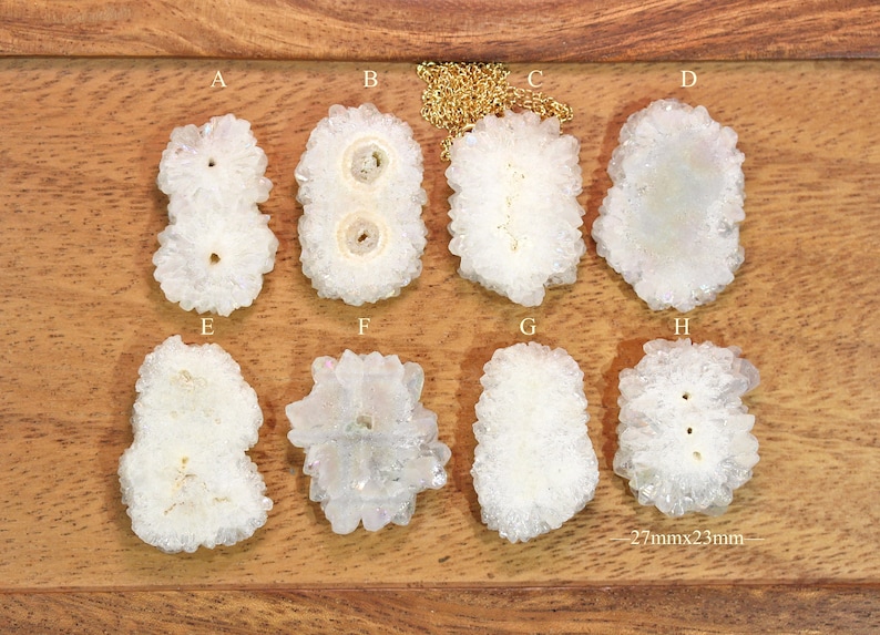 May include: Eight white quartz crystal pendants, each with a unique shape and size, arranged in two rows of four on a wooden surface. The pendants measure approximately 2.7 inches by 2.3 inches.