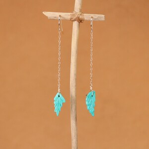 May include: A pair of silver dangle earrings with turquoise leaf-shaped charms.