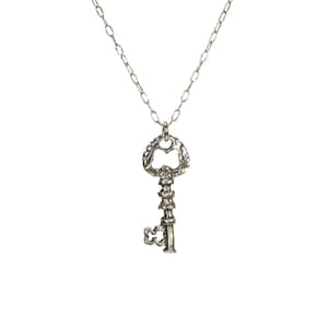 Puede incluir: Un collar de plata con un colgante de llave adornado. La llave tiene un dise&ntilde;o detallado y un gran ojo de cerradura.