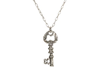 May include: A silver key necklace with an ornate key pendant. The key has a detailed design and a large keyhole.