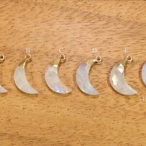 May include: Six gold-plated crescent moon charms with white moonstone. Each charm is approximately 1.5 inches by 0.6 inches.