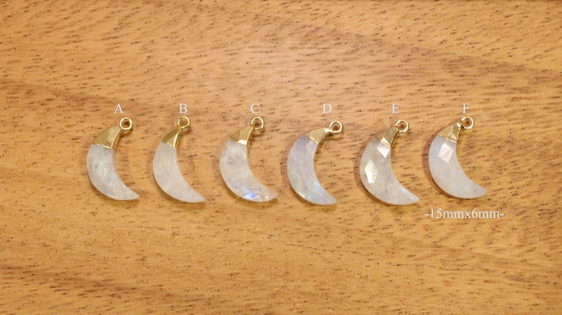May include: Six gold-plated crescent moon charms with white moonstone. Each charm is approximately 1.5 inches by 0.6 inches.
