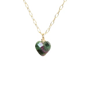May include: A gold chain necklace with a green and pink heart-shaped pendant.