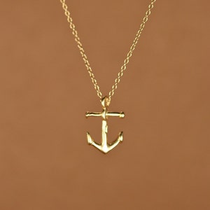May include: A gold anchor pendant necklace on a delicate chain.