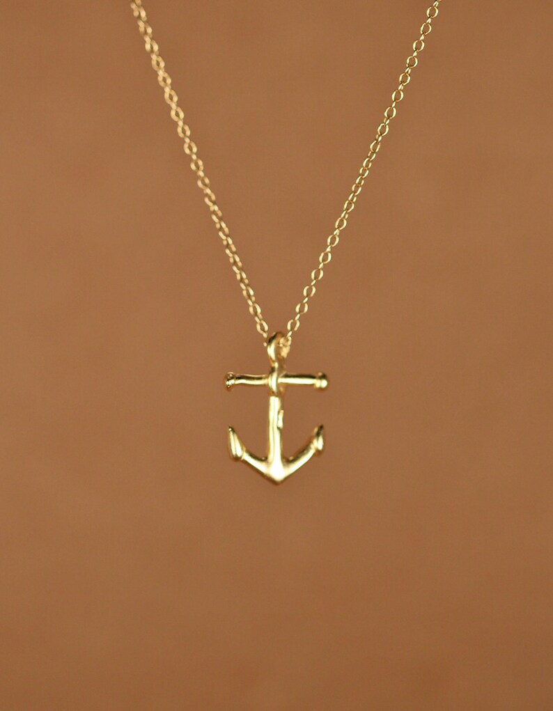 May include: A gold anchor pendant necklace on a delicate chain.