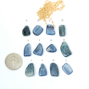 May include: Twelve blue kyanite stones of varying shapes and sizes, arranged in rows on a white surface. A US dime is included for scale.