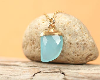May include: A gold necklace with a light blue gemstone pendant. The pendant is shaped like a crescent moon and has a gold trim.