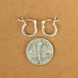 May include: A pair of silver hoop earrings, shown next to a US dime for size comparison.