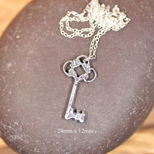 May include: Silver key pendant necklace with a detailed ornate design. The key measures 24mm x 12mm.