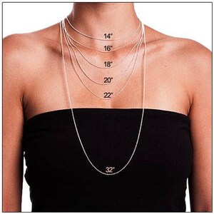 May include: A silver chain necklace is shown on a model wearing a black top. The necklace is shown in different lengths, from 14 inches to 32 inches.
