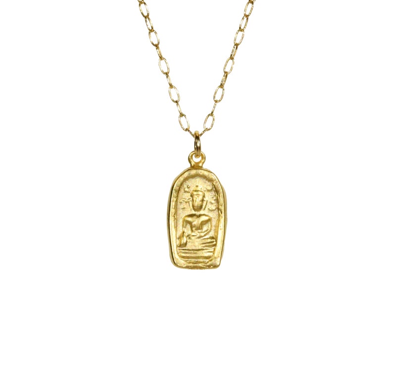 May include: A gold necklace with a pendant featuring a detailed image of a seated Buddha. The pendant is in the shape of a rectangle with rounded edges.