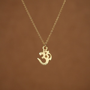 May include: A gold chain necklace with an Om symbol pendant.