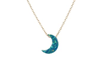 Puede incluir: Un collar de cadena dorada con un colgante de media luna de ópalo azul.