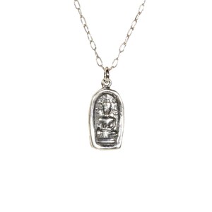 May include: A silver chain necklace with a pendant featuring a small, detailed image of a seated Buddha figure.