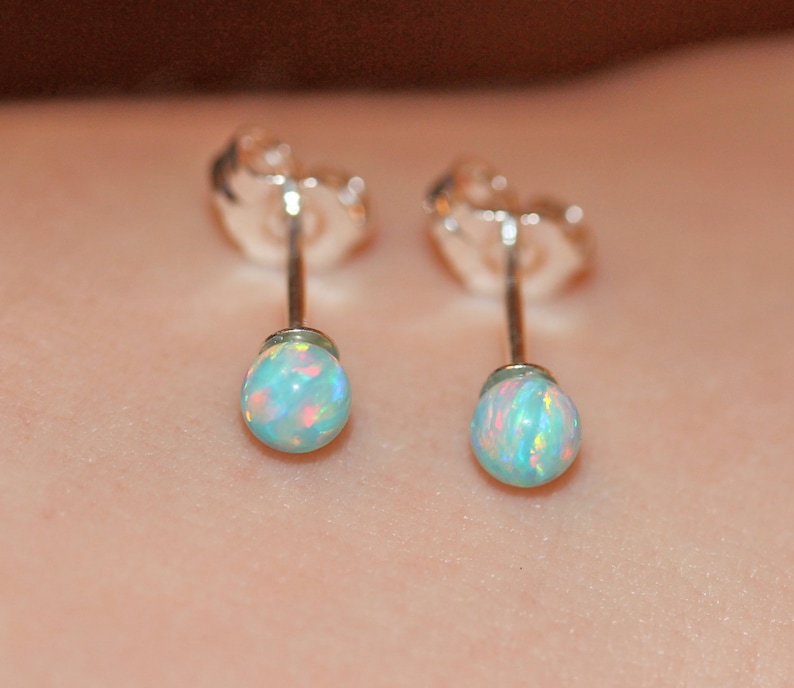 May include: A pair of silver stud earrings with small, round, iridescent opal stones.