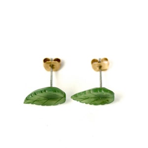 May include: A pair of green jade leaf earrings with gold posts. The leaves are carved with delicate veins.