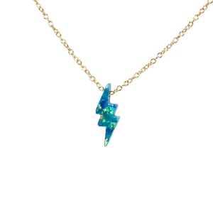 May include: A gold chain necklace with a blue opal lightning bolt pendant.