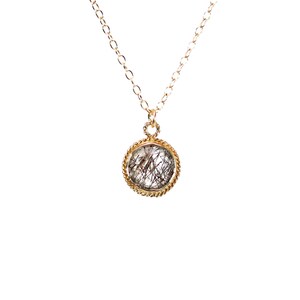 May include: A gold chain necklace with a round pendant featuring a clear quartz stone with black inclusions.