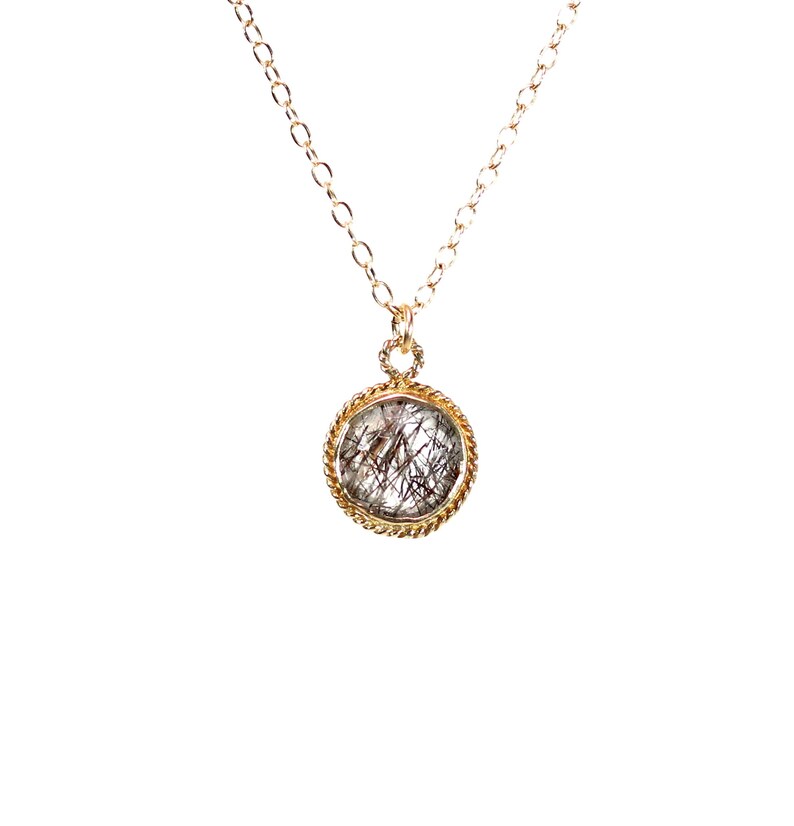 May include: A gold chain necklace with a round pendant featuring a clear quartz stone with black inclusions.