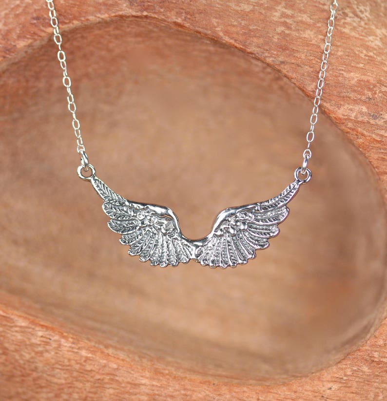 Puede incluir: Un collar de plata con un colgante de ala de &aacute;ngel detallado. Las alas est&aacute;n extendidas y tienen un dise&ntilde;o delicado e intrincado.