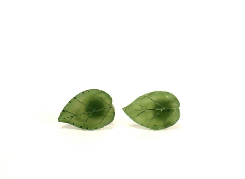 May include: A pair of green leaf-shaped earrings. The earrings are made of a translucent green material and have a delicate vein pattern.